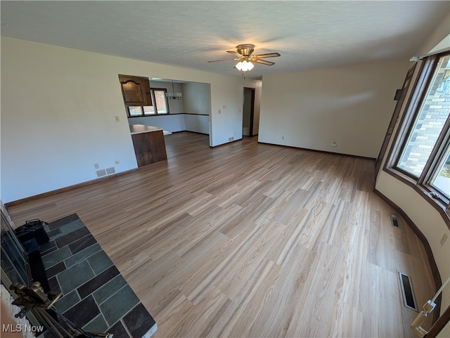 unfurnished living room with light wood-type flooring, a textured ceiling, plenty of natural light, and ceiling fan