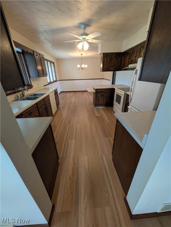 kitchen featuring kitchen peninsula, light wood-type flooring, white range with electric stovetop, dark brown cabinetry, and sink