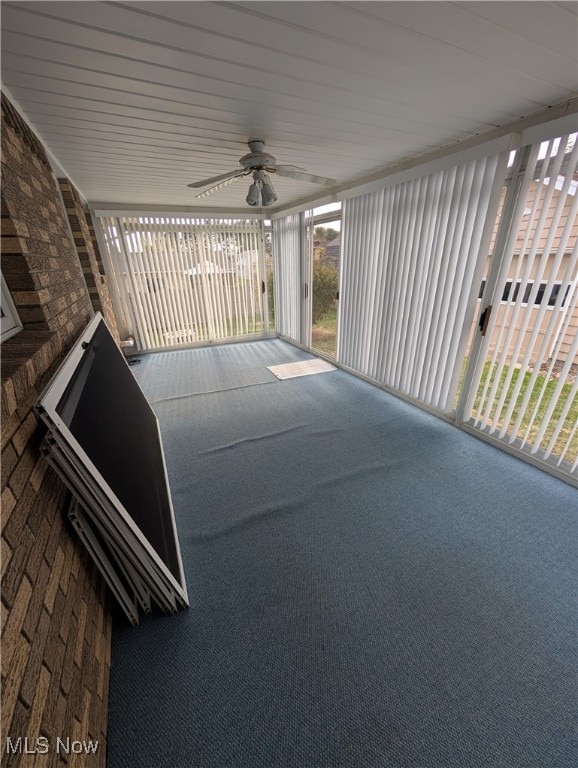 unfurnished sunroom featuring ceiling fan, a wealth of natural light, and wood ceiling