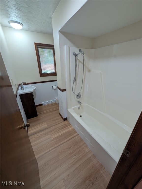 bathroom featuring vanity, washtub / shower combination, and wood-type flooring