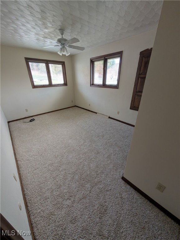 carpeted spare room with a textured ceiling and ceiling fan