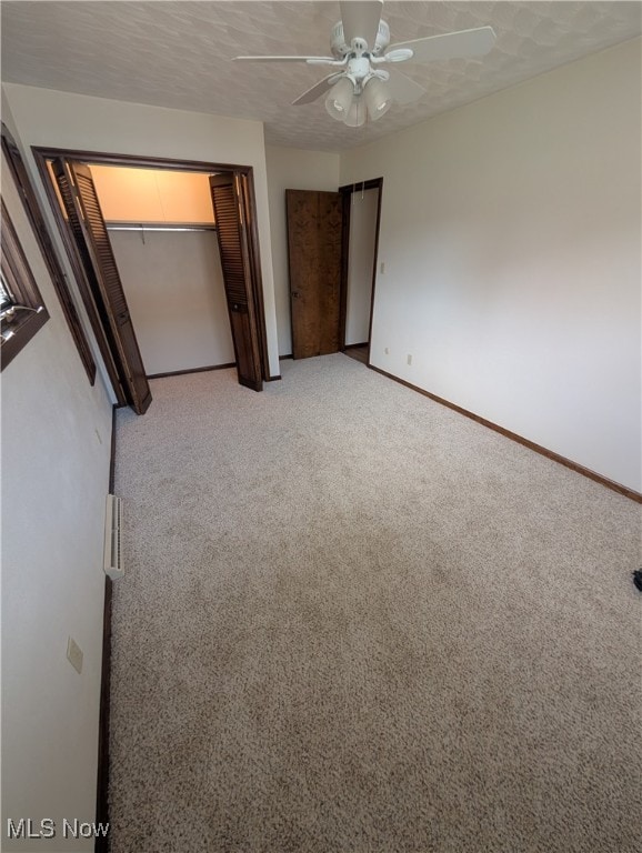 unfurnished bedroom featuring a closet, ceiling fan, carpet, and a textured ceiling