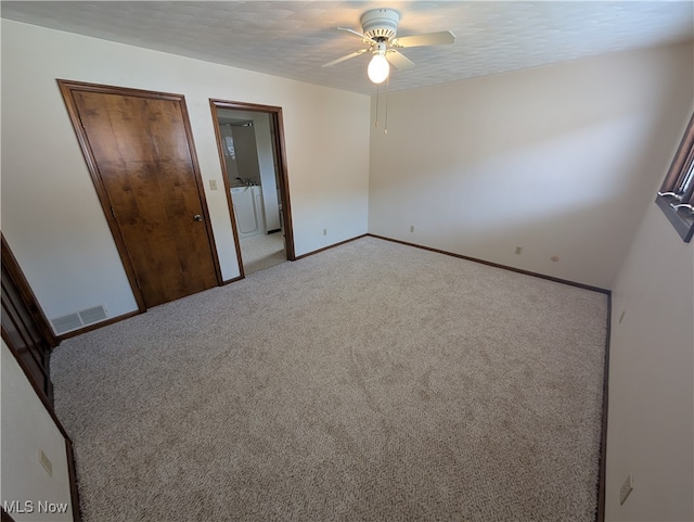 unfurnished bedroom featuring a textured ceiling, carpet floors, separate washer and dryer, and ceiling fan