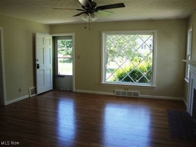 spare room with ceiling fan, a healthy amount of sunlight, and dark hardwood / wood-style flooring