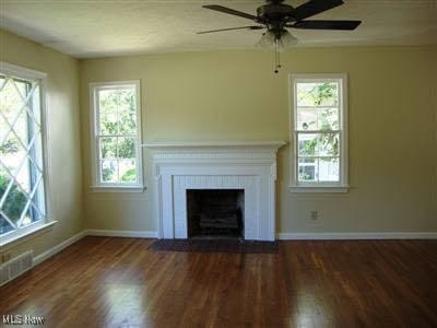 unfurnished living room featuring dark hardwood / wood-style floors, a fireplace, and ceiling fan