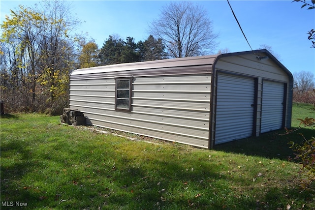 view of outdoor structure featuring a garage and a lawn