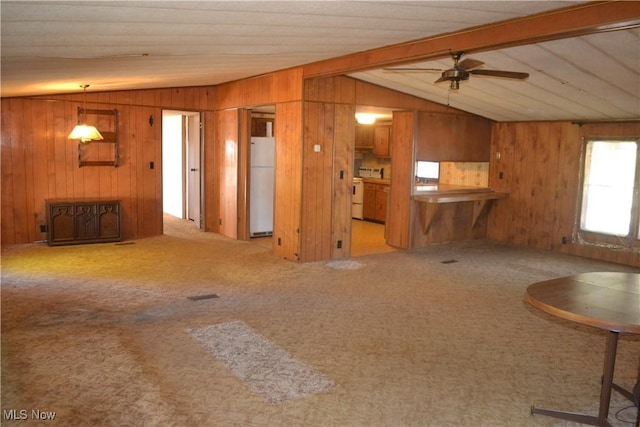 unfurnished living room featuring lofted ceiling with beams, carpet flooring, ceiling fan, and wood walls