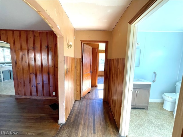 hallway featuring wooden walls and dark hardwood / wood-style floors