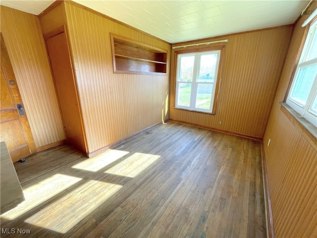 unfurnished room with wood walls and light wood-type flooring