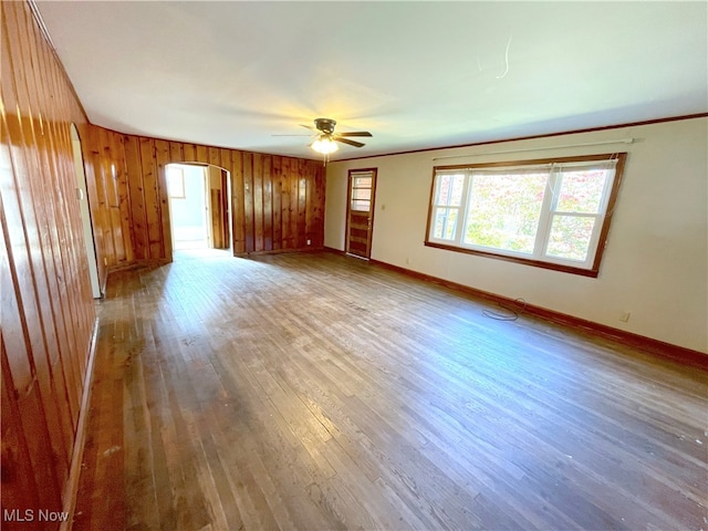 spare room with hardwood / wood-style floors, ceiling fan, and wood walls