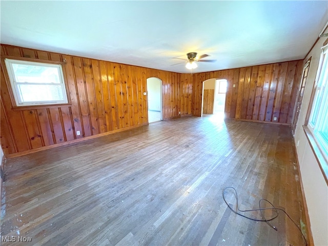 empty room with wood walls, hardwood / wood-style flooring, and ceiling fan