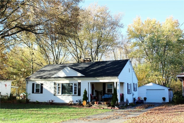 view of front of home with covered porch, an outdoor structure, a front yard, and a garage