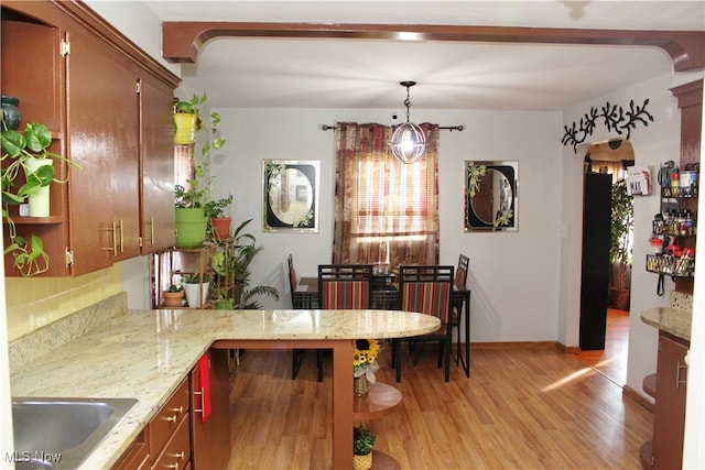 kitchen featuring kitchen peninsula, decorative backsplash, hanging light fixtures, light hardwood / wood-style floors, and sink