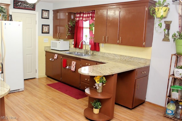 kitchen featuring kitchen peninsula, decorative backsplash, light wood-type flooring, sink, and white appliances