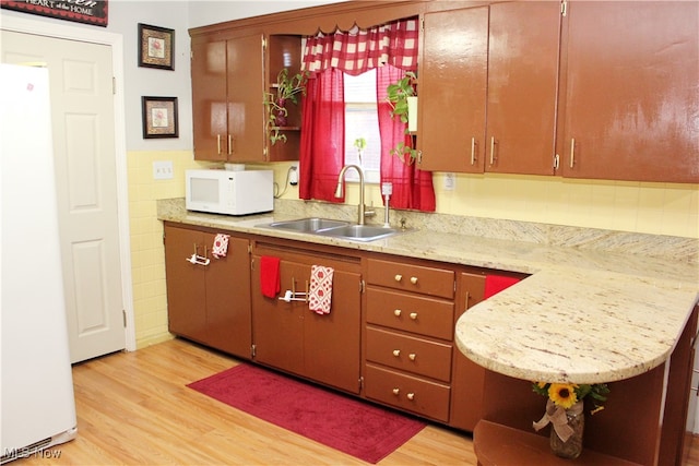 kitchen featuring white appliances, light hardwood / wood-style floors, sink, and kitchen peninsula