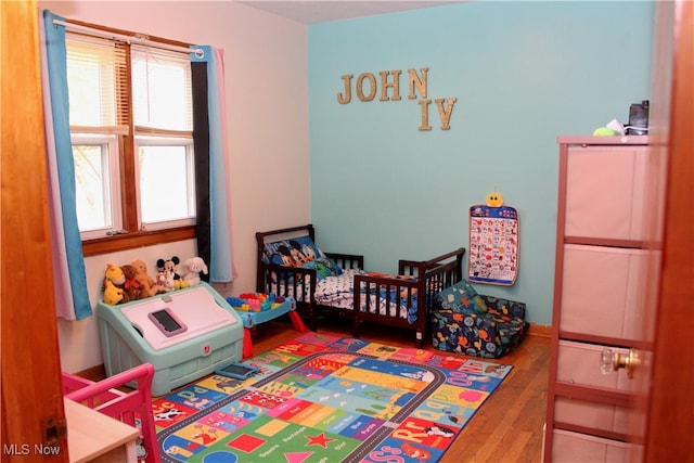 bedroom with a nursery area and hardwood / wood-style flooring