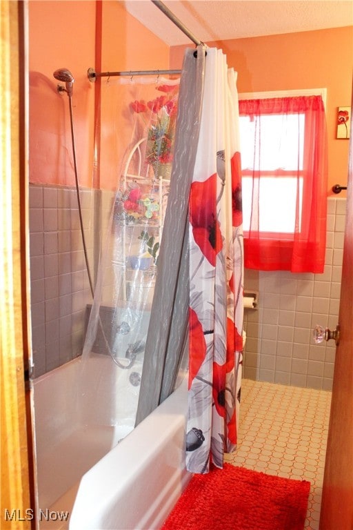 bathroom with shower / bathtub combination with curtain and tile walls