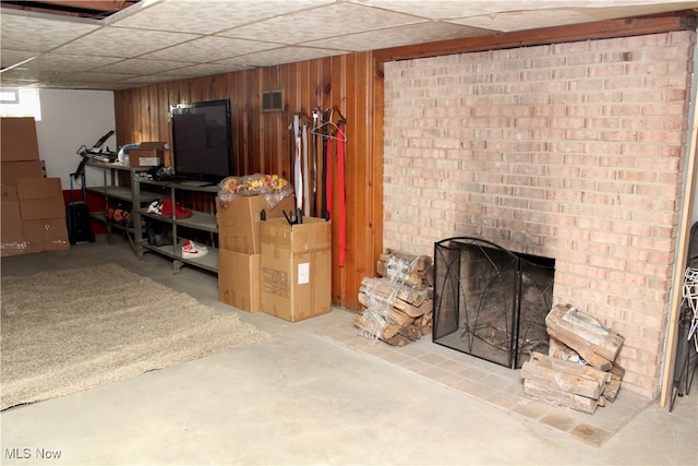 basement featuring wooden walls and a fireplace