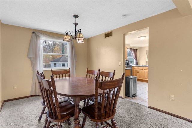 carpeted dining area with a textured ceiling and a notable chandelier