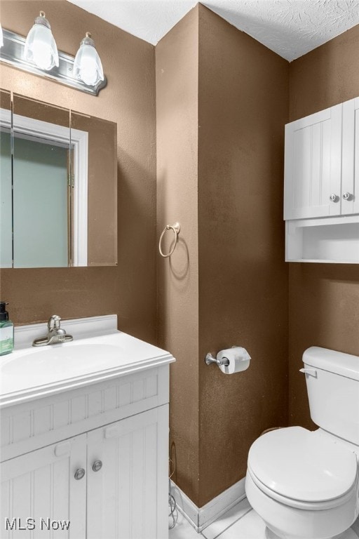 bathroom featuring vanity, a textured ceiling, and toilet