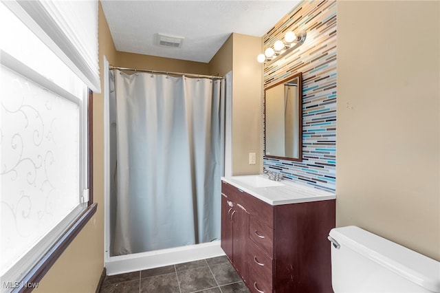 bathroom with decorative backsplash, vanity, a healthy amount of sunlight, and toilet