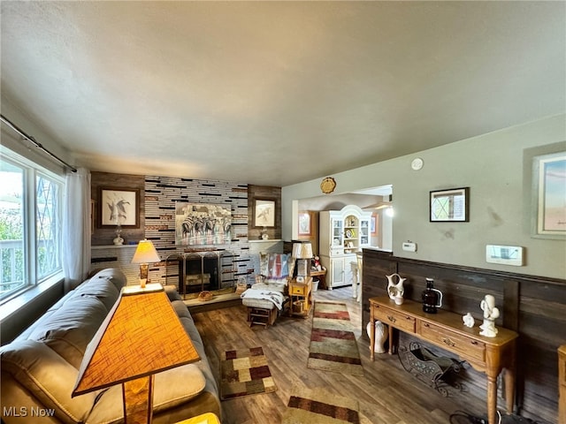 living room featuring a fireplace, wood-type flooring, and wood walls