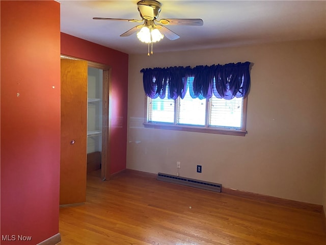 empty room featuring ceiling fan, light hardwood / wood-style flooring, and a baseboard heating unit