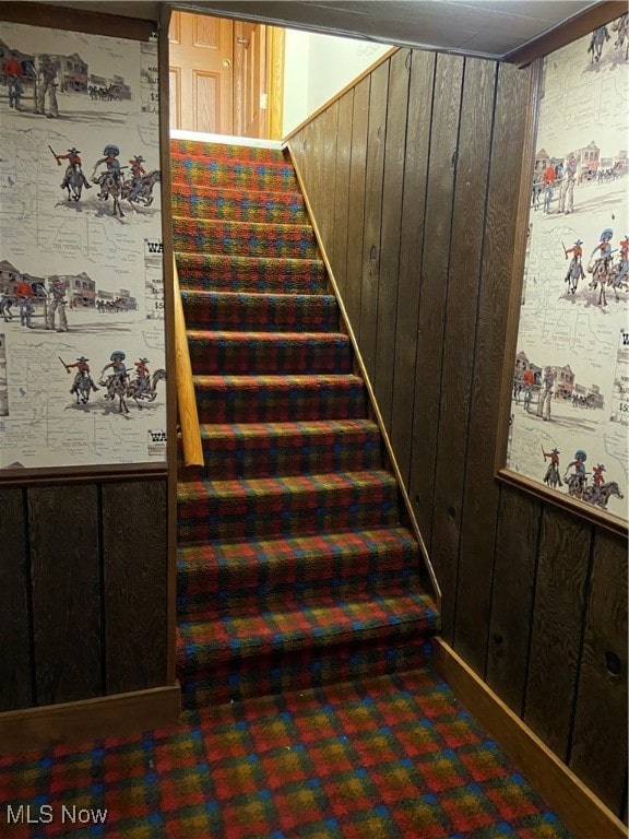 staircase featuring wooden walls