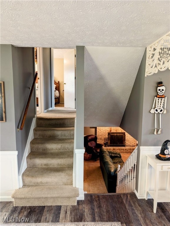 staircase featuring lofted ceiling, a textured ceiling, and hardwood / wood-style flooring