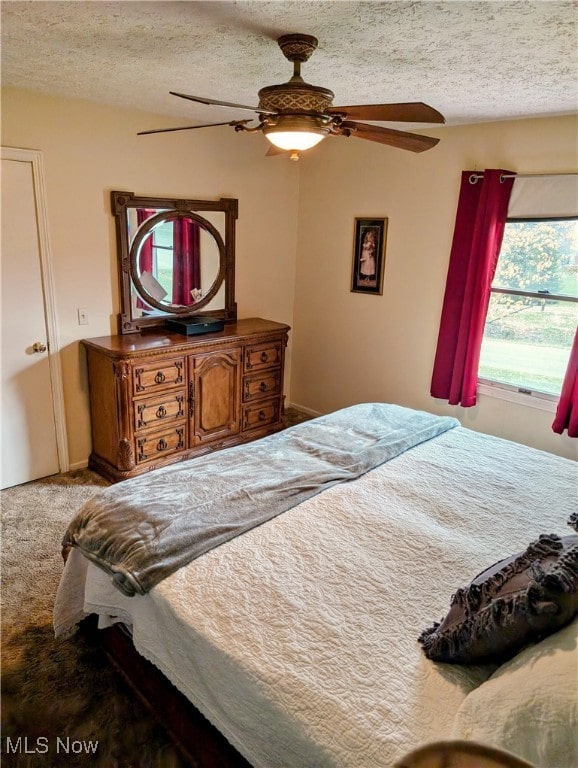 carpeted bedroom with ceiling fan and a textured ceiling