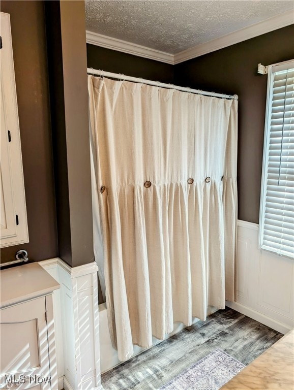 bathroom with hardwood / wood-style flooring, a textured ceiling, and ornamental molding