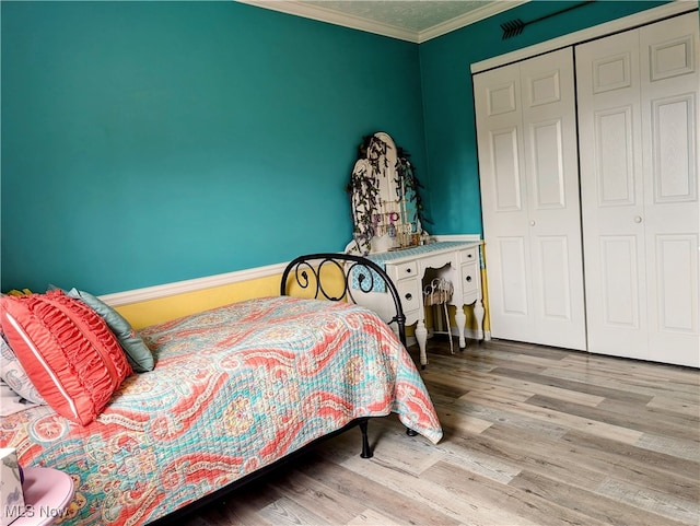 bedroom featuring light hardwood / wood-style floors, a closet, and crown molding