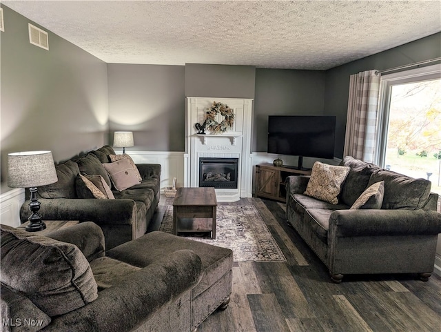 living room with a textured ceiling and dark hardwood / wood-style floors