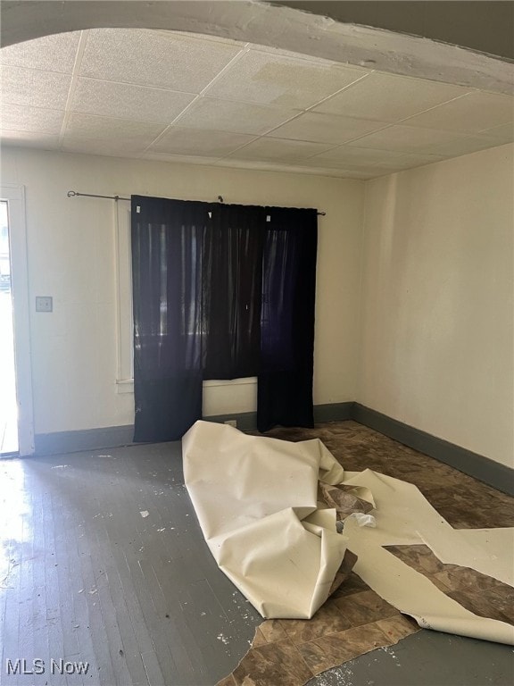 unfurnished bedroom with dark wood-type flooring and a drop ceiling