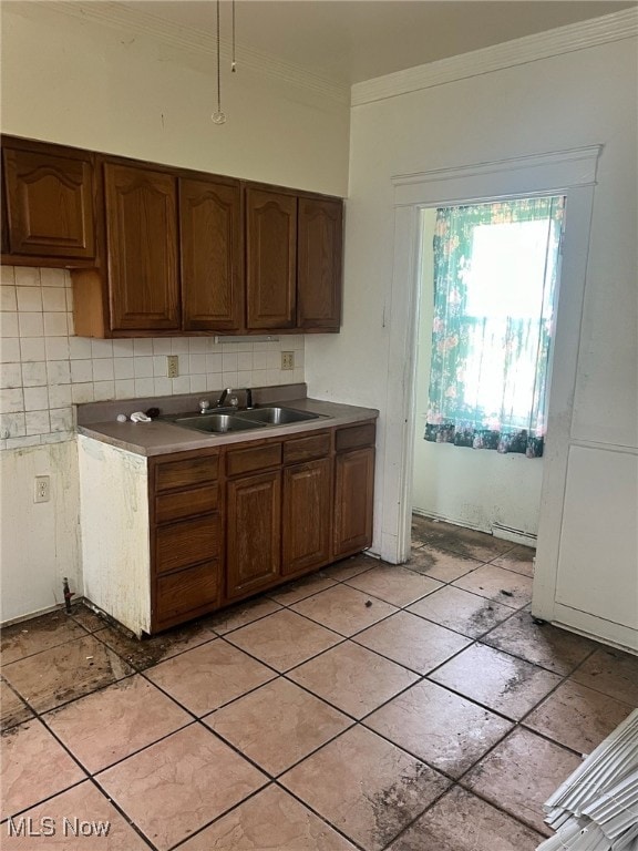 kitchen featuring baseboard heating, sink, decorative backsplash, and crown molding