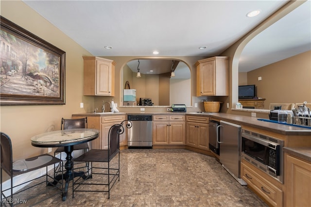 kitchen with sink, kitchen peninsula, light brown cabinetry, and appliances with stainless steel finishes