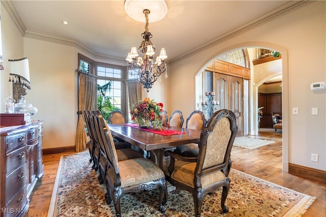 dining area with crown molding, a notable chandelier, and light wood-type flooring