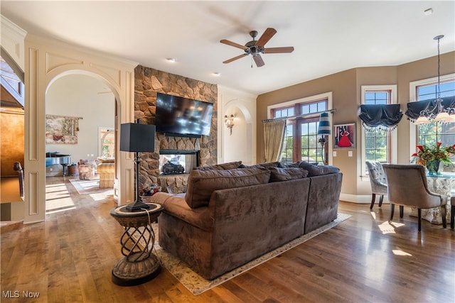 living room with dark hardwood / wood-style floors, a stone fireplace, and ceiling fan