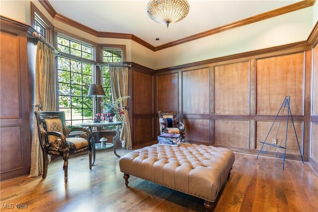 sitting room featuring a decorative wall, wood finished floors, and ornamental molding