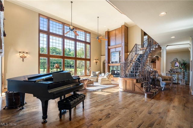 miscellaneous room featuring decorative columns, crown molding, ceiling fan, and hardwood / wood-style flooring