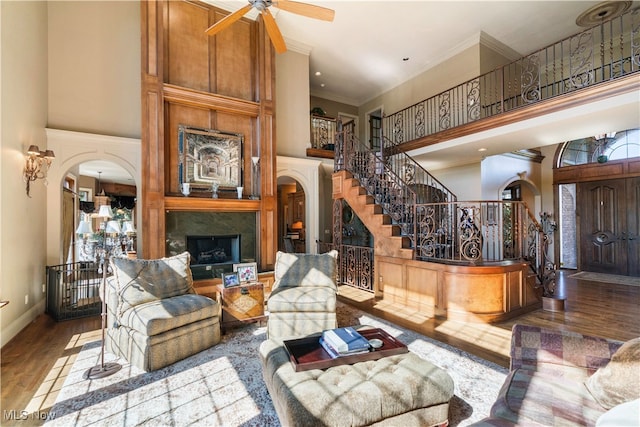 living room with ceiling fan, hardwood / wood-style floors, crown molding, and a high ceiling