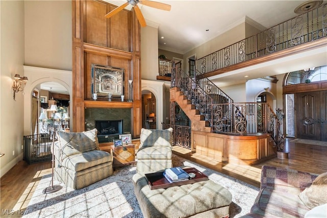 living room featuring arched walkways, a towering ceiling, and wood finished floors