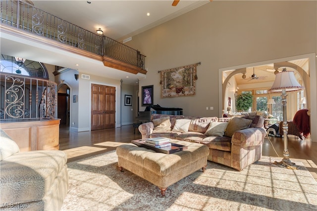 living room with ceiling fan, ornamental molding, and a high ceiling