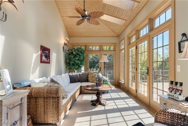 sunroom / solarium with lofted ceiling with skylight, ceiling fan, a healthy amount of sunlight, and wood ceiling