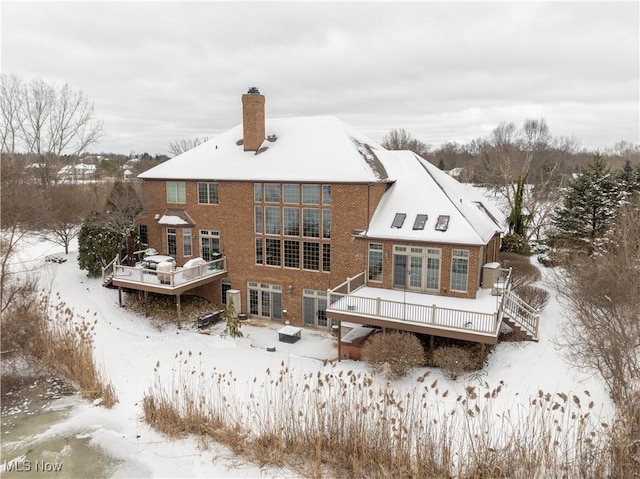 snow covered back of property featuring a wooden deck