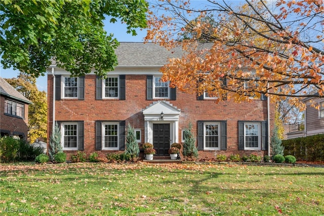 colonial-style house featuring a front lawn