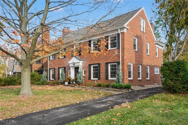 colonial-style house featuring a front lawn