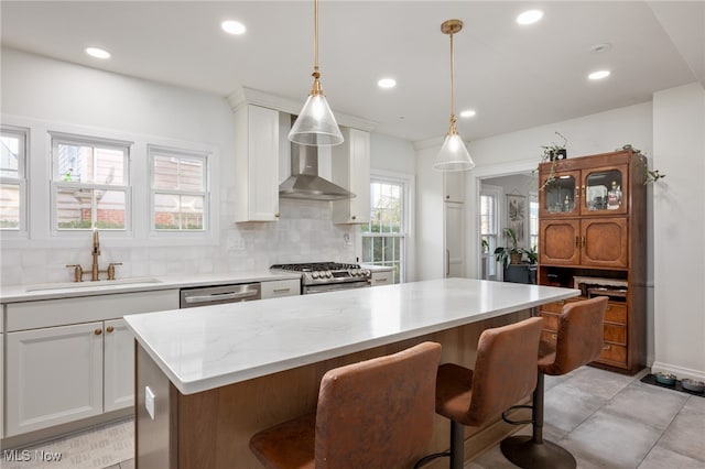 kitchen with stainless steel appliances, sink, a center island, white cabinetry, and tasteful backsplash