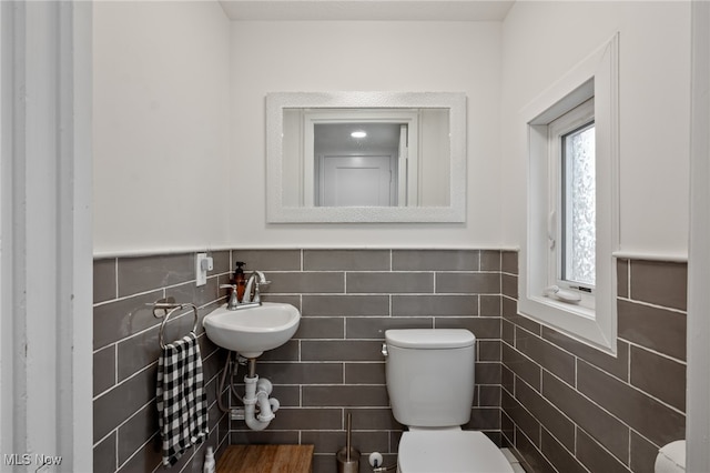 bathroom with toilet, tile walls, and sink