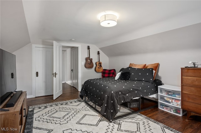 bedroom with a closet, vaulted ceiling, and dark hardwood / wood-style flooring